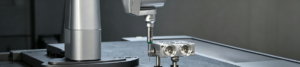 Industrial CMM coordinate measuring machine inspects precision machined parts in workshop. High accuracy 3D dimensional measurement for CNC manufactured components.